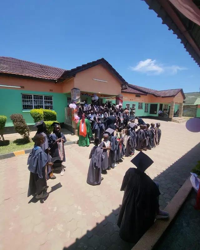 Quick Step pupils in graduation gowns lining up in the Meanwood campus courtyard