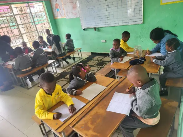 Pupils writing in their exercise books at the PHI campus